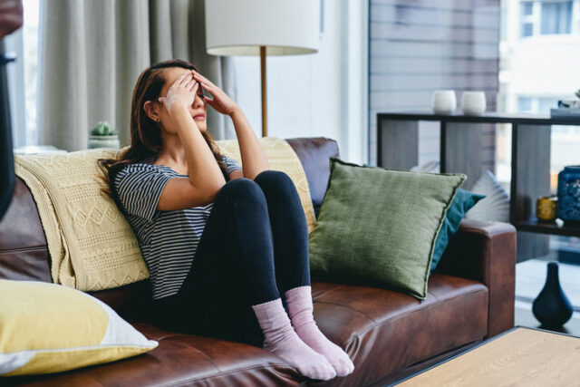 anxious woman sitting alone on couch