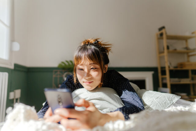 smiling woman texting in bed